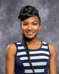 Young African-American woman with a long braided hairstyle wearing a blue striped top.
